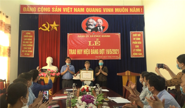 Đồng chí Hoàng Thanh Sơn Uỷ viên Ban thường vụ Huyện ủy, Chỉ huy trưởng BCHQS huyện trao huy hiệu và tặng hoa chúc mừng đảng viên Nông Quyết Định